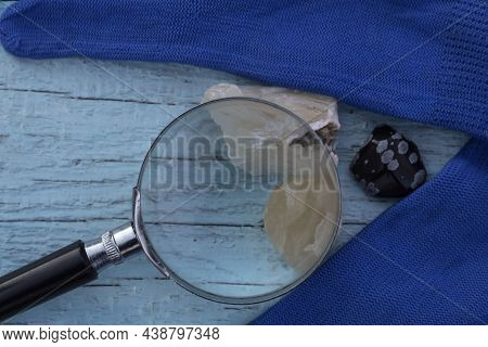 Close-up. A Magnifying Lens And Three Semiprecious Stones - Stilbite, Yellow Quartz And Snow Obsidia