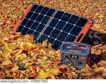 Fort Collins, CO, USA - November 4, 2021: Jackery Explorer 500, 518Wh lithium Portable Power Station, is being charged by a solar panel in a field covered by colorful dry leaves.