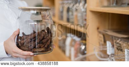 A Woman Holds Croutons In A Glass Jar. Eco Shop Without Plastic Waste.