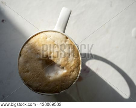 A Close-up Of A Ceramic Glass With Coffee And A Thick Foam Of Milk On The Table. Topv View. The Hars