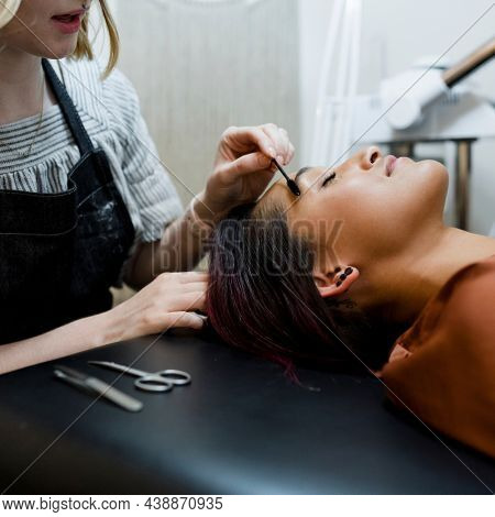 Beautician giving eyebrow treatment to a customer at a beauty salon
