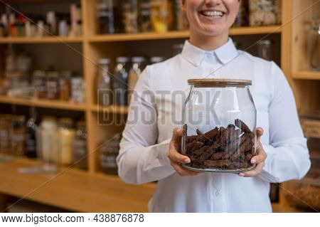 A Woman Holds Croutons In A Glass Jar. Eco Shop Without Plastic Waste.