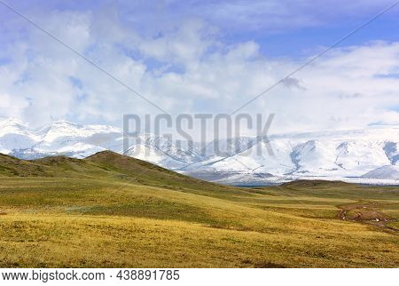 Kurai Steppe In Spring. Dry Grass On The Slopes, Snow-capped Peaks Of The Mountains Of The Northern 