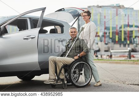 Full Length Portrait Of Mature Couple With Man In Wheelchair By Car In Parking Lot Outdoors, Copy Sp