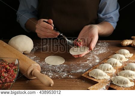 Woman Putting Gyoza Filling In Center Of Dough Wrapper At Wooden Table, Closeup