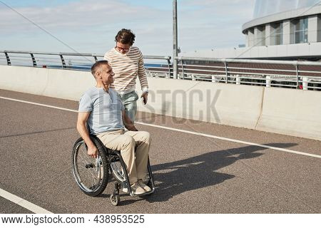 Full Length Portrait Of Mature Couple With Man In Wheelchair Chatting Outdoors And Enjoying City Lif