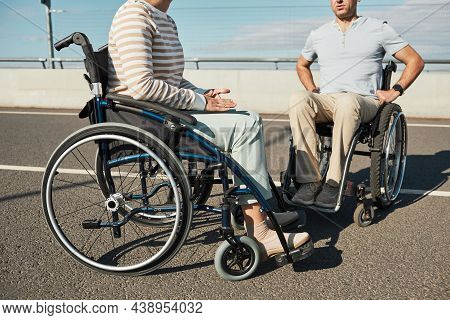 Cropped Portrait Of Adult Couple In Wheelchairs Chatting Outdoors In Sunlight And Enjoying City Life