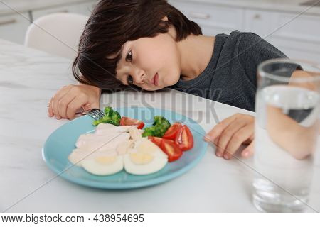 Cute Little Boy Refusing To Eat Dinner In Kitchen
