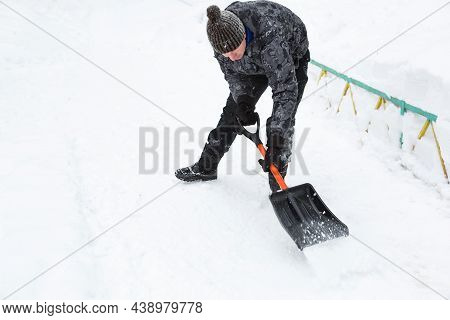 A Man Cleans Snow With A Shovel In Winter In A Swept Yard After A Snowfall. Winter Weather Condition