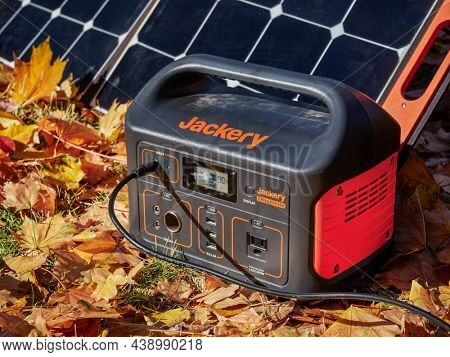 Fort Collins, CO, USA - November 4, 2021: Jackery Explorer 500, 518Wh lithium Portable Power Station, is being charged by a solar panel in a field covered by colorful dry leaves.