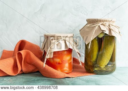 Pickles, Canned Vegetables In Glass Jars And A Terracotta Linen Napkin On A Light Green Background. 