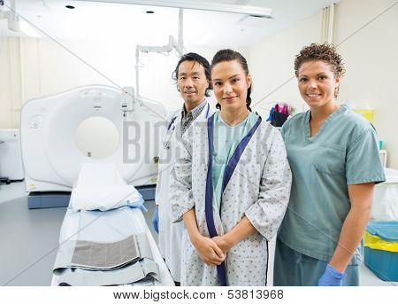 Portrait of medical team with patient smiling in CT scan room