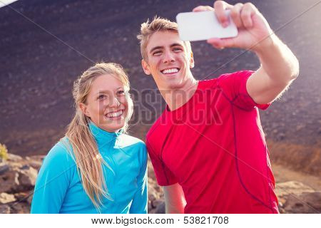 Young attractive athletic couple taking photo of themselves with smart phone, making a selfie