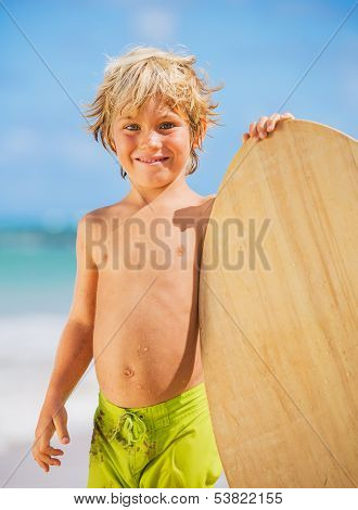 Happy Young boy having fun at the beach on vacation, with skimboard