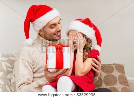 family, christmas, x-mas, winter, happiness and people concept - smiling daughter with closed eyes waiting for a present from fathe