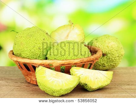 Osage Orange fruits (Maclura pomifera) in basket, on wooden table, on nature background