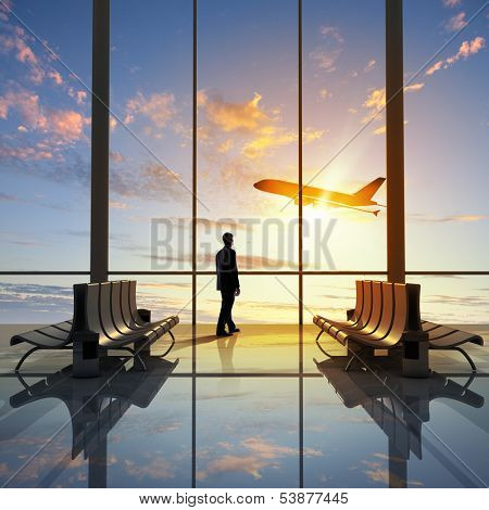 Businessman at airport looking at airplane taking off