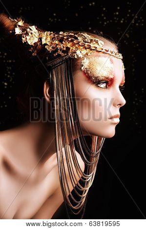 Art project: beautiful woman with golden make-up. Jewelry, make-up. Fashion. Over black background.