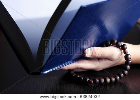 Hands with rosary and holy book, on light background