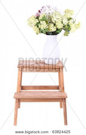 Vase with flowers on small wooden ladder, isolated on white
