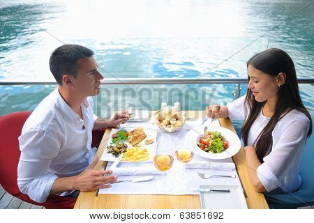 happy young couple having lanch at beautiful restaurant on by the sea on  beach