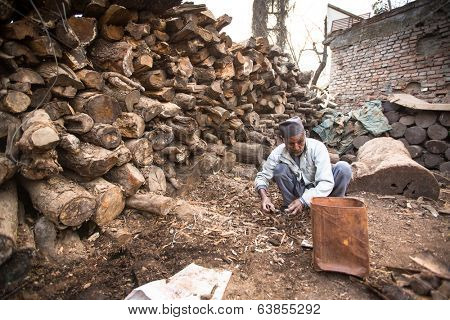 KATHMANDU, NEPAL - DEC 19, 2013: Unidentified a man sort wood for cremation rites in Bhasmeshvar Ghat at Pashupatinath temple in Kathmandu. 
