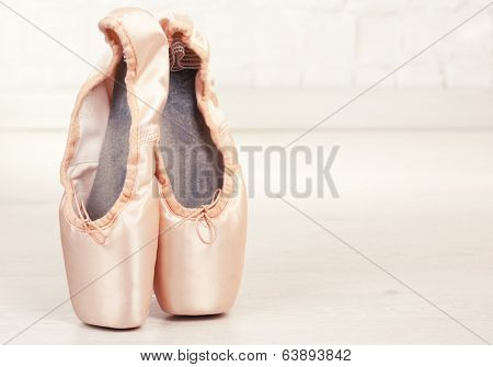 Ballet pointe shoes on floor in dance hall