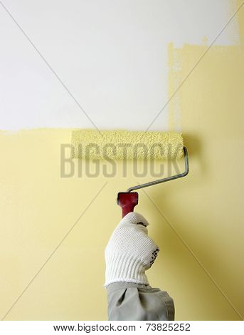 Hand painting a white wall with a paint roller 