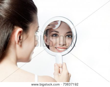 closeup portrait of attractive  caucasian smiling woman brunette isolated on white studio shot lips toothy smile face hair head and shoulders looking at  mirror cleaning face cotton disc