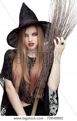 Portrait of young woman in witch costume with a broom