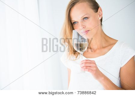 Gorgeous young woman with a glass of wine, smelling the lovely drink, savouring every sip (shallow DOF; color toned image)