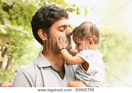 Indian Father holding daughter lovingly. Nature background