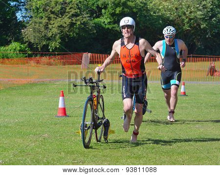 Triathlon Men running in to change over with bikes.