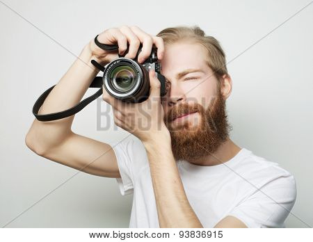 Travel, technology and life style concept: young bearded  photographer taking pictures with digital camera.