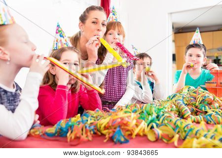 Children having birthday party with fun blowing streamers, group of kids with mother