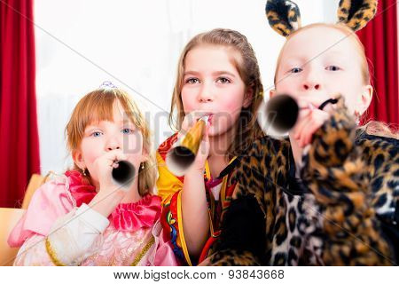 Kids with noisemakers making noise on party looking into the camera