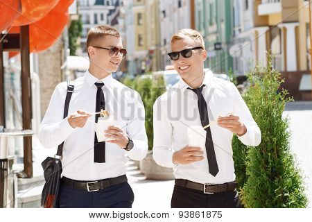 Pair of young men walking with street food