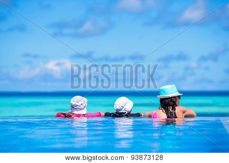 Mother and two kids enjoying summer vacation in luxury swimming pool