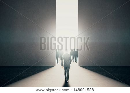 Businessman walking towards abstract opening with bright light and people silhouettes in concrete interior. Success concept. 3D Rendering