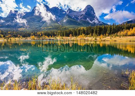 The concept of recreational tourism. Bright shining day in the Canadian Rockies. Canmore, near Banff National Park. Majestic mountains and red-orange trees 