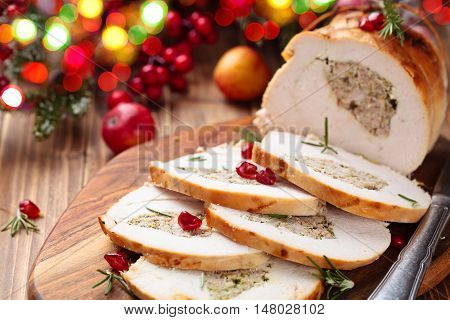 Stuffed turkey breast with pomegranate and rosemary on cutting board.