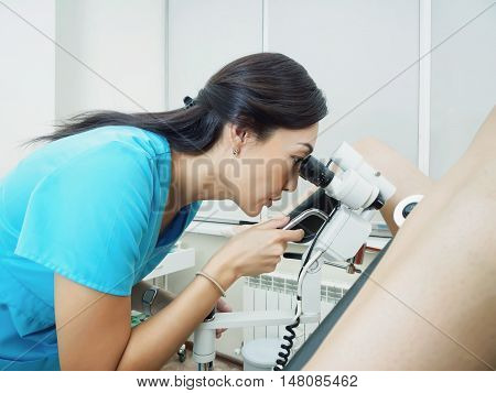 Asian woman gynecologist examining patient in hospital using a colposcope