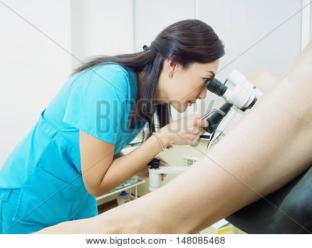 Asian woman gynecologist examining patient in hospital using a colposcope