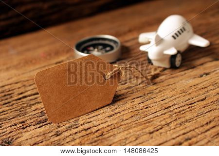 paper tag or label with pastic airplane toy and compass on woodenconcept idea for travelbusiness