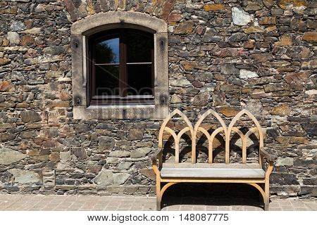 carved wooden bench on stone wall background window on facade of old building