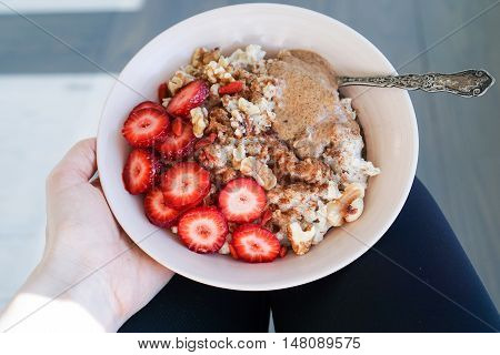 Tasty cinnamon oatmeal, steel cut oats with strawberry and nuts, nut butter. Breakfast Scene.