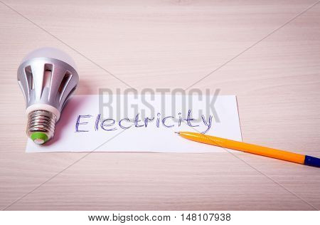 Energy saving light bulb on a table with an inscription and a pen