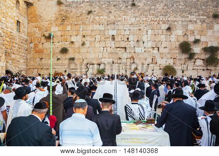 JERUSALEM, ISRAEL - OCTOBER 12, 2014:  The area in front of Western Wall of Temple filled with people. The Jews of ritual clothes - tallit hold four ritual plants. Sukkot, Blessing of the Kohanim