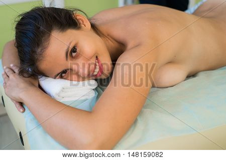 Portrait of a smiling beautiful woman ready for massage at beauty spa.