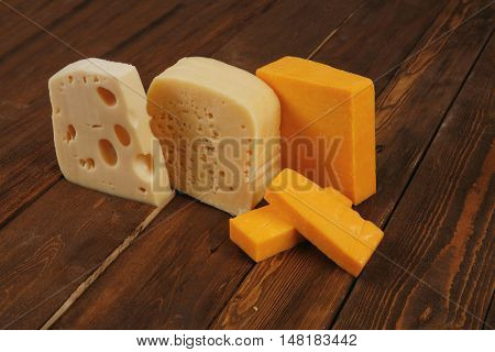 various types of fresh raw aged delicatessen cheese on wooden table cheddar edam swiss